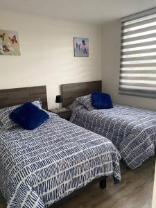 two beds in a bedroom with blue and white sheets at Departamento a minutos del centro de Puerto Montt Pelluco alto in Puerto Montt