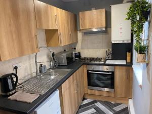 una pequeña cocina con armarios de madera y fregadero en Aspen House - Apartment 1, en Colwyn Bay