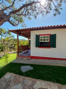 a small white house with a red and green window at Chalés Vila das Cachoeiras in Diamantina