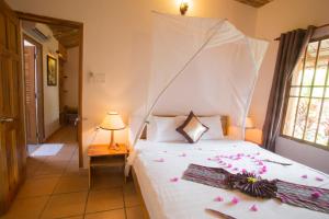 a bedroom with a white bed with flowers on it at La Mer Resort, Phú Quốc in Phú Quốc