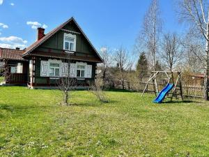 uma casa com um quintal com um escorrega e um parque infantil em Leśne PoBudki em Białowieża