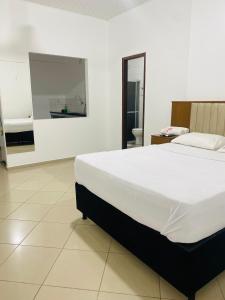 a bedroom with a large white bed and a bathroom at Hotel SALINE PRAIA in Salinópolis