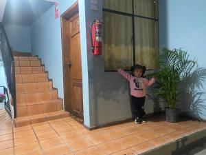 uma menina parada no canto de uma sala em Hostal Locuras en el Cielo em Baños