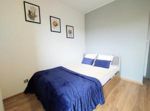 a bedroom with a bed with a blue blanket on it at Garden Apartment in Wieliczka