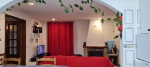 a living room with a red couch and a red curtain at Casa O Arco Alojamento Local in Marvão