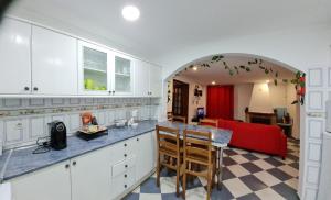 une cuisine avec des placards blancs et un canapé rouge dans l'établissement Casa O Arco Alojamento Local, à Marvão