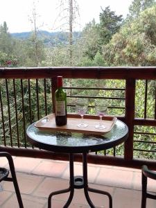 Una botella de vino y dos copas en una mesa en un balcón. en La Casona Del Retiro, en Medellín
