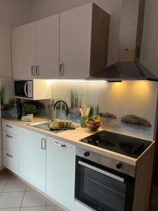 uma cozinha com armários brancos e um forno com placa de fogão em Apartments Adriapag em Pag