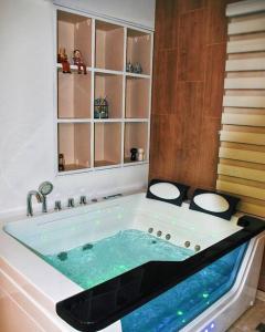 a bathroom with a jacuzzi tub with blue water at Havana Zimmer צימר הוואנה in Majdal Shams