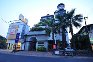 a building with a palm tree in front of it at Hotel Arcadia in Kottayam