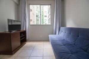 ein Wohnzimmer mit einem blauen Sofa und einem Fenster in der Unterkunft STH52 - Quadra Mar, 4 Dorm, Centro, Climatizado in Balneário Camboriú