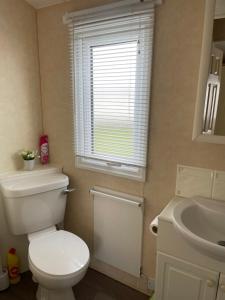 une salle de bain avec toilettes, lavabo et fenêtre dans l'établissement Golden Palm Resort MV194, à Chapel St. Leonards 18 autres photos