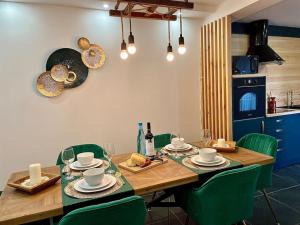 una mesa de comedor con sillas verdes y una cocina en Zambujeira Terrace en Zambujeira do Mar