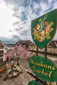 a sign for a restaurant in a town with flowering trees at Hotel-Restaurant Weinhaus Grebel in Koblenz
