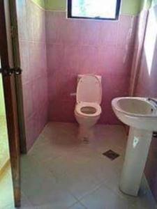 une salle de bains rose avec toilettes et lavabo. dans l'établissement Family Friendly Entire House 4 minutes to Beach, à Liloan