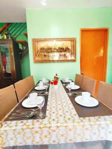 une salle à manger avec une table, des assiettes et des verres dans l'établissement Family Friendly Entire House 4 minutes to Beach, à Liloan