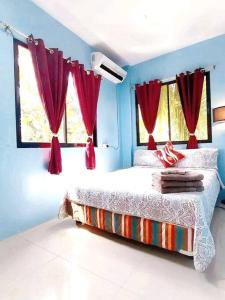 a blue bedroom with a bed with red curtains at Family Friendly Entire House 4 minutes to Beach in Liloan