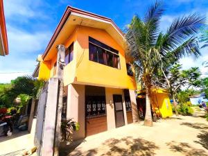 a yellow house with a palm tree in front of it at Family Friendly Entire House 4 minutes to Beach in Liloan
