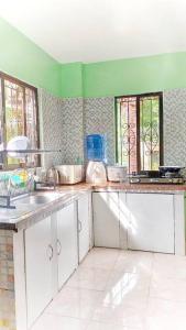 a kitchen with white cabinets and green walls and windows at Family Friendly Entire House 4 minutes to Beach in Liloan