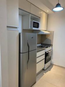 a kitchen with a stainless steel refrigerator and a microwave at Departamento para 4 personas, con cochera, a metros del centro de la ciudad in Rosario
