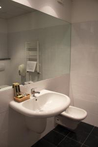 uma casa de banho com um lavatório branco e um espelho. em Essenza Hotel em Verrès
