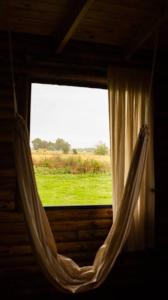 a window with a hammock looking out at a green field at Cabañas El Sosiego in Azul