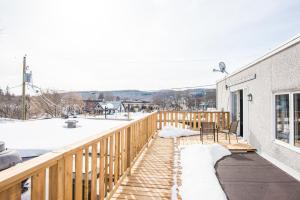 a balcony with a wooden railing and a table and chairs at Le Downtown Tremblant • Logement in Mont-Tremblant