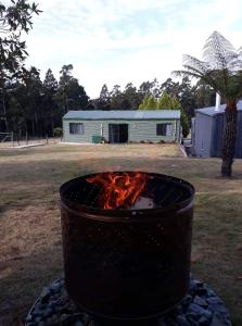 una hoguera en un patio con un edificio al fondo en Cabin in the Tasmanian Bush - Tranquility! en Pipers River