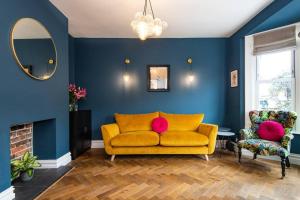 a yellow couch in a blue living room with a mirror at Newly renovated Victorian house with free parking in Portslade