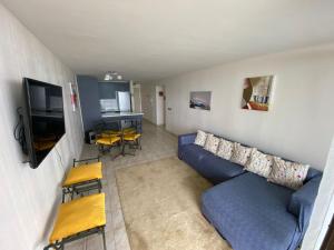 a living room with a blue couch and a tv at Departamento vista al mar in El Tabo