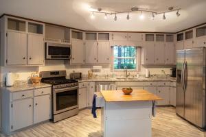 cocina con armarios blancos y encimera de madera en Manders Manor, en Perry