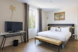 um quarto com uma cama e uma televisão de ecrã plano em Hôtel La Villa Cap d’Antibes em Juan-les-Pins