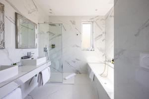 a white bathroom with a sink and a mirror at Hôtel La Villa Cap d’Antibes in Juan-les-Pins