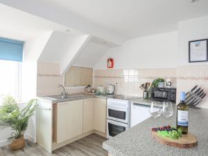 a kitchen with white appliances and a table with a bottle of wine at Ysgo - 6 Ty'n Don in Abersoch