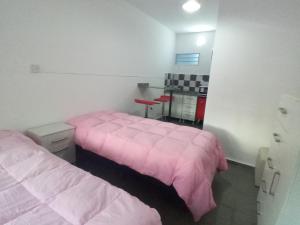 Dos camas en una habitación con sábanas rosas. en Departamento Marques, en Santa Rosa 2 fotos más