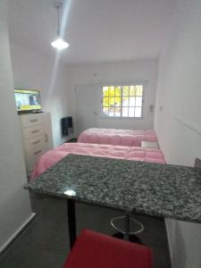 Un dormitorio con dos camas y una mesa con sábanas rosas. en Departamento Marques, en Santa Rosa