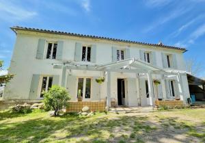 Hostens的住宿－Entre Chênes et Pins - Gîte de groupe 3 étoiles，一座带庭院的大型白色房屋