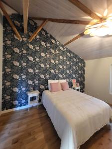 een slaapkamer met een bed met een bloemaccentmuur bij Entre Chênes et Pins - Gîte de groupe 3 étoiles in Hostens