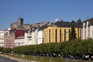 a row of buildings next to a river with trees at Hôtel Paradis in Lourdes