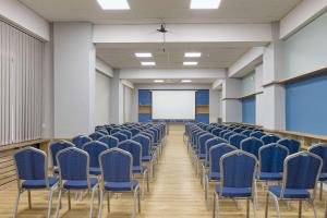 uma sala de conferências vazia com cadeiras e um ecrã branco em Best Western Tbilisi Art Hotel em Tbilisi