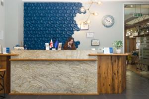a woman talking on a cell phone behind a counter at Best Western Tbilisi Art Hotel in Tbilisi City