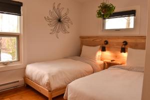 two beds in a room with two windows at Complexe d'hébergement la Maison touristique Dugas in Caraquet