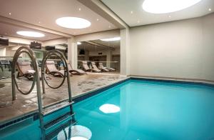 a swimming pool in a hotel room with chairs at Southern Sun Cape Sun in Cape Town