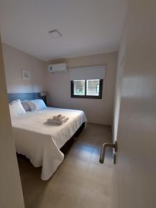 a bedroom with a white bed with a window at Complejo El Olivo in San Martín