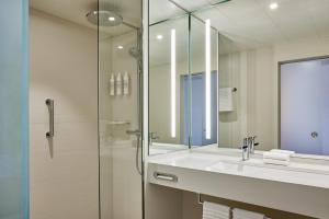 a bathroom with a sink and a glass shower at Le Méridien Frankfurt in Frankfurt/Main