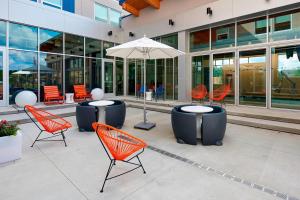 a group of chairs and an umbrella in front of a building at Aloft Cleveland Airport in North Olmsted