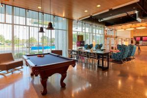 a pool table in the middle of a room with chairs at Aloft Cleveland Airport in North Olmsted