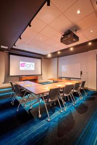 a conference room with a table and chairs and a screen at Aloft Cleveland Airport in North Olmsted