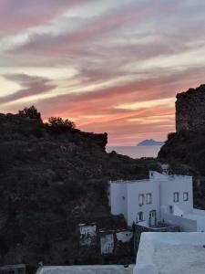 a sunset over a hill with white buildings and a castle at Spiliani View in Mandrakion