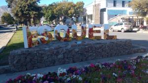 a sign that says smile in a stone wall with flowers at La Casa de Kuky in Esquel
